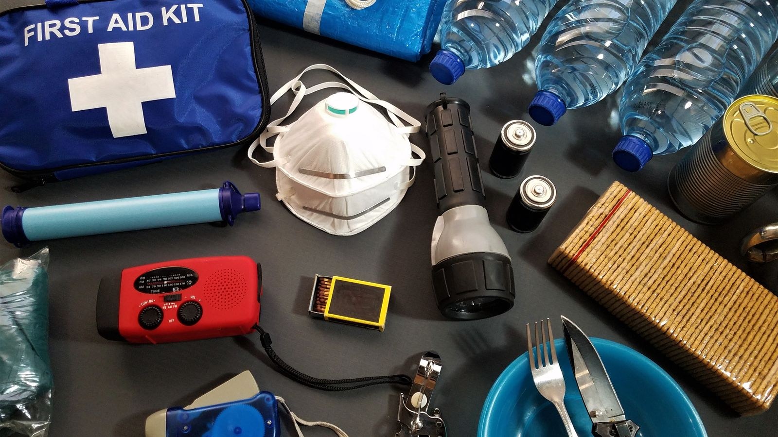 Flat lay of 72-hour home emergency kit supplies including water bottles and first aid items