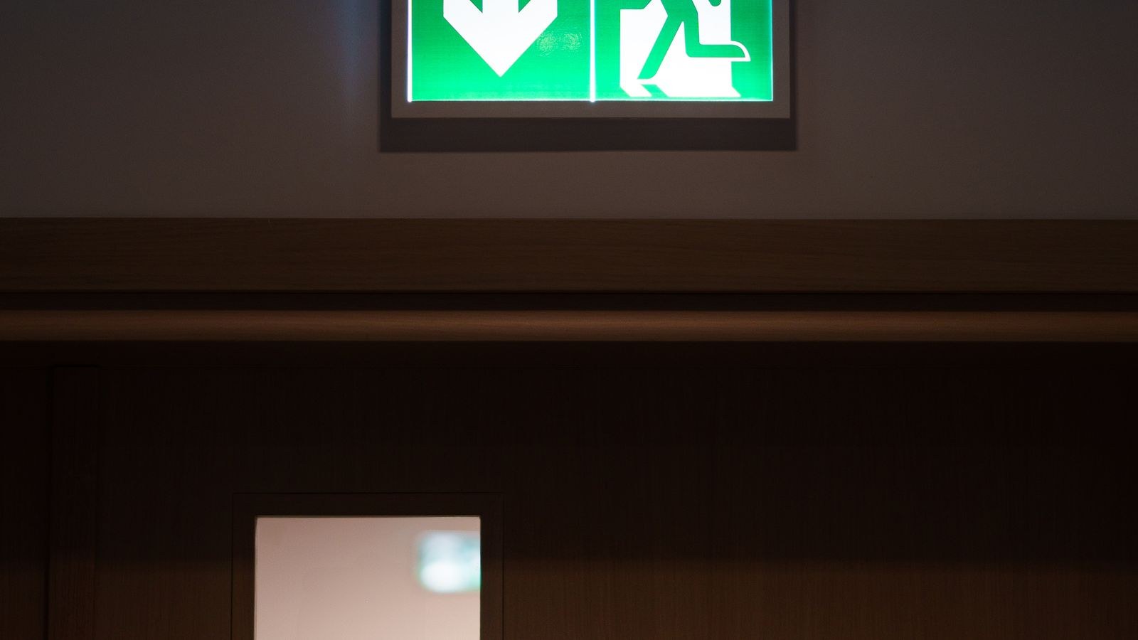 Green emergency exit sign above a door marking a second way out