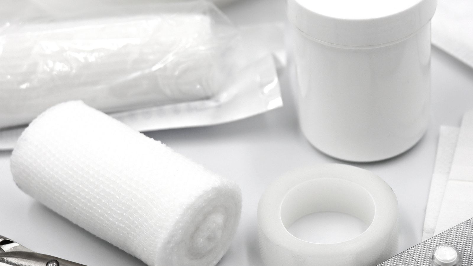 Flat lay of essential first aid supplies including bandages safety pins and medication