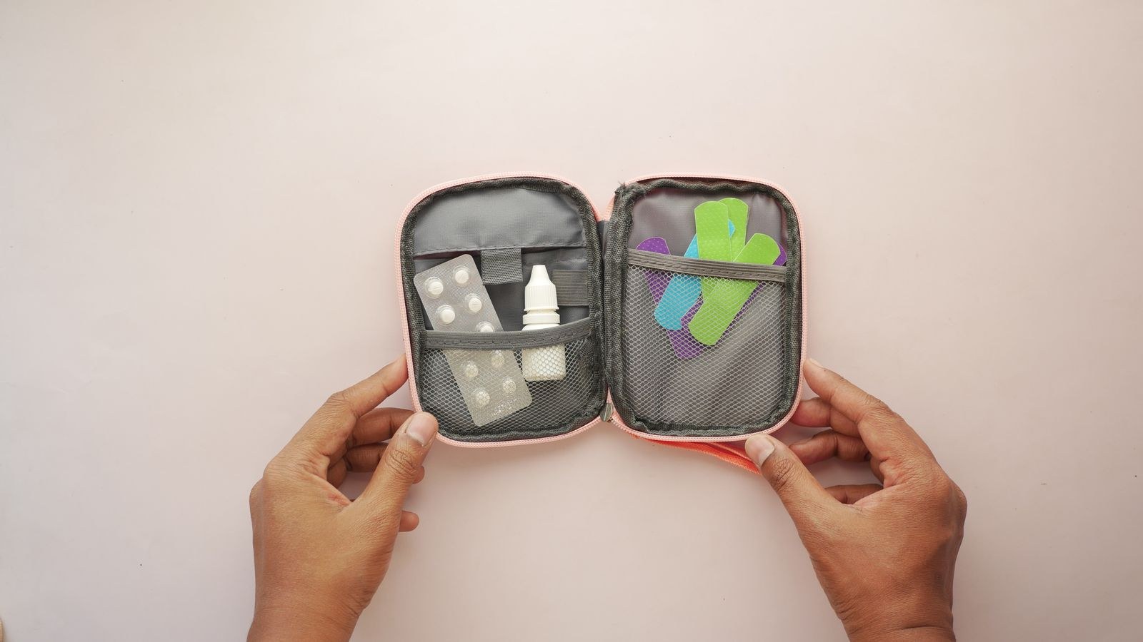 Open first aid kit with plasters tablets and medicines held in both hands