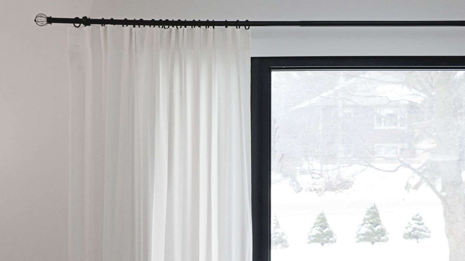 Wide living room window with floor length curtains on a long curtain rod