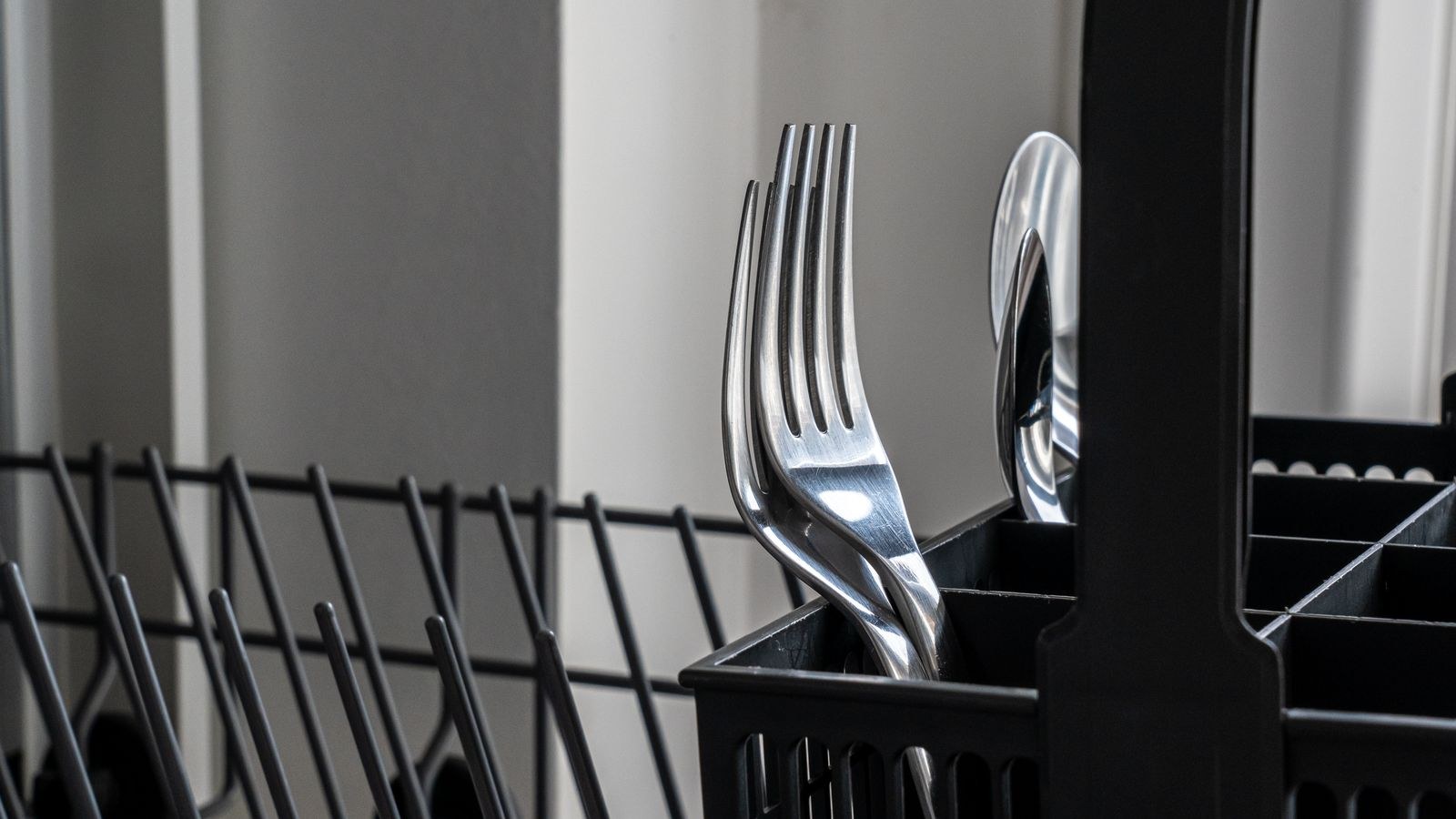 Close-up of stainless steel cutlery in a dishwasher rack