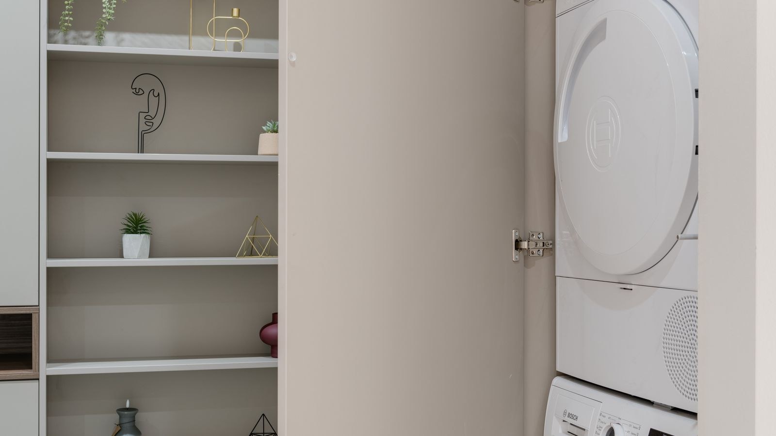 Stacked washer and dryer set installed in a cabinet with duct access behind