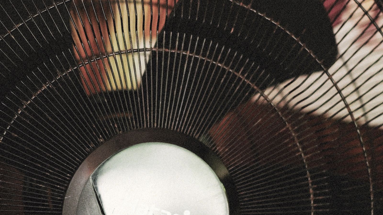 Close-up of a fan grille and blades showing dust buildup on the metal slats