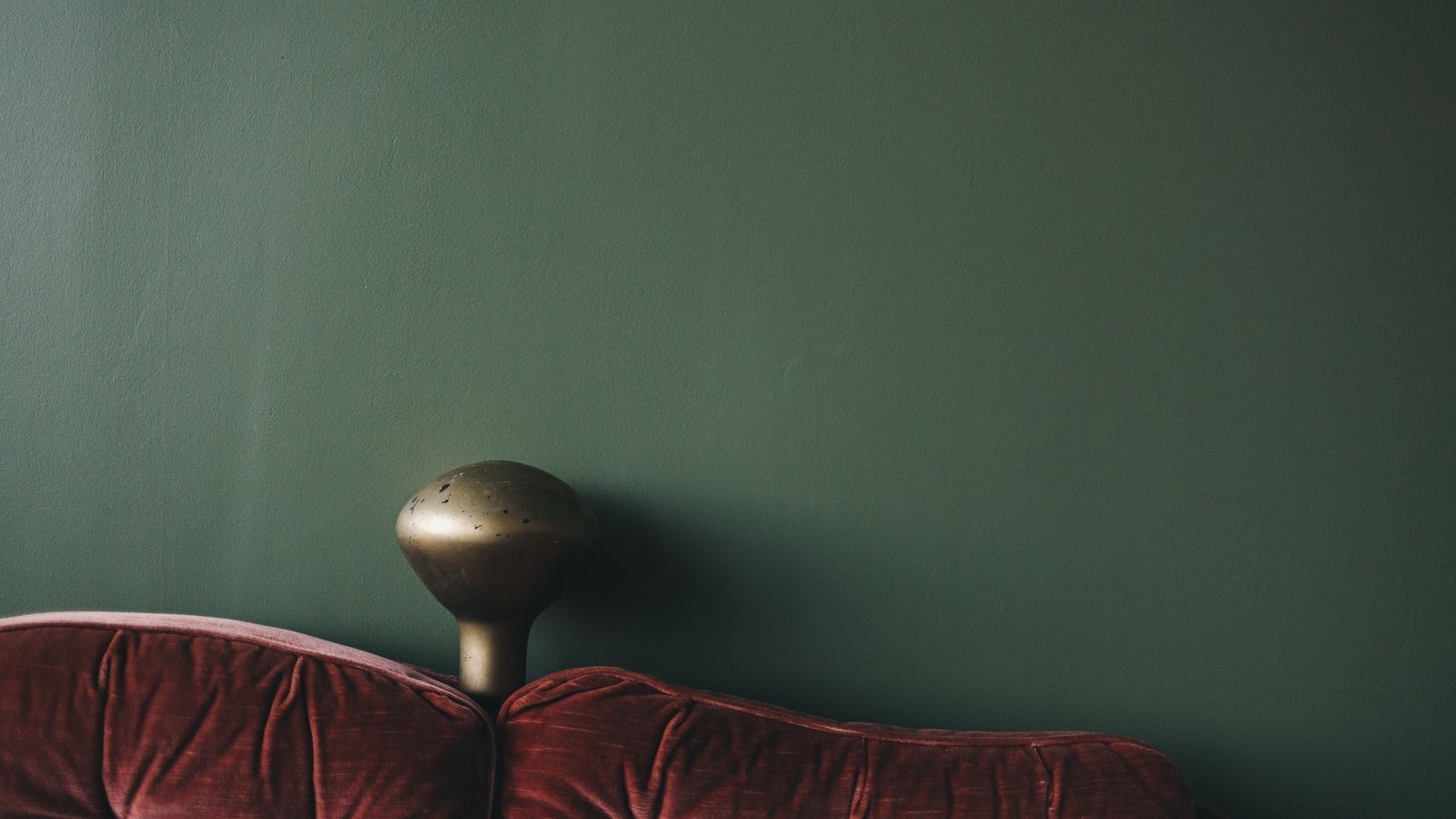 Green velvet sofa against a dark wall showing rich pile texture