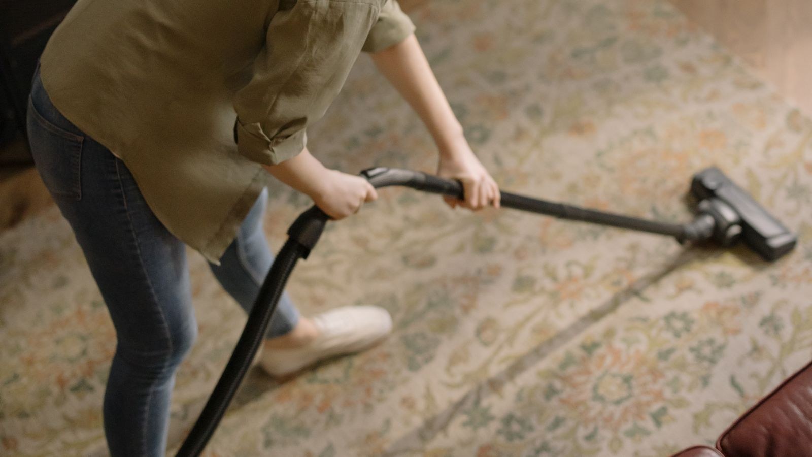 Person vacuuming a patterned area rug in a stylish living room