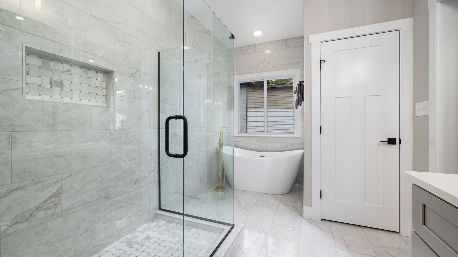 Clear glass shower door enclosure in a modern tiled bathroom
