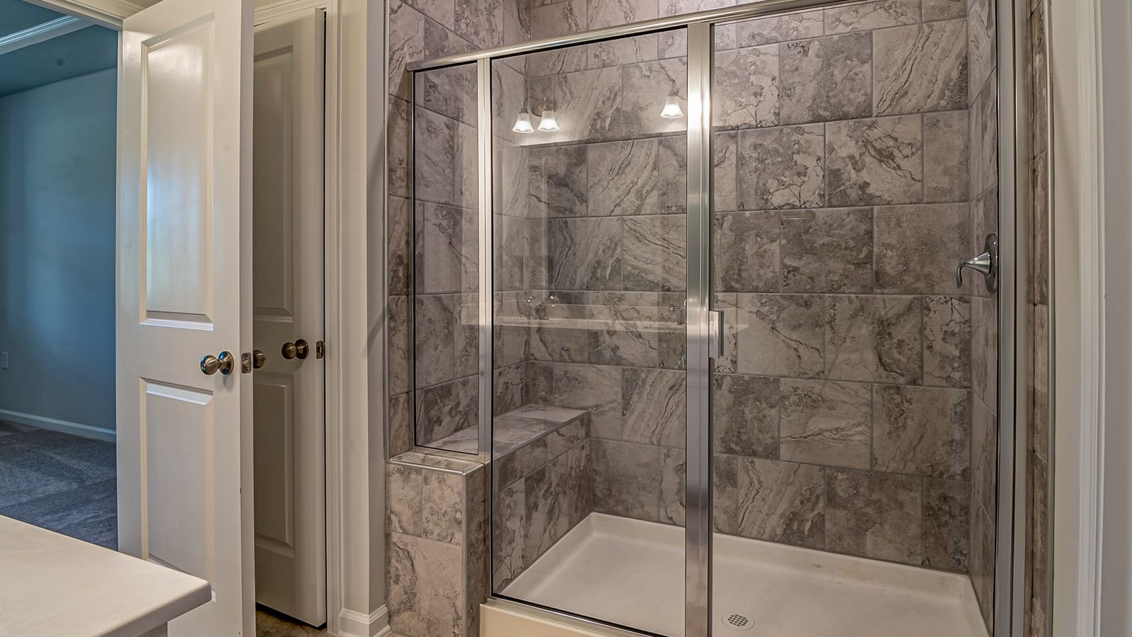 Squeegee wiping water droplets from a glass shower door to prevent hard water stains