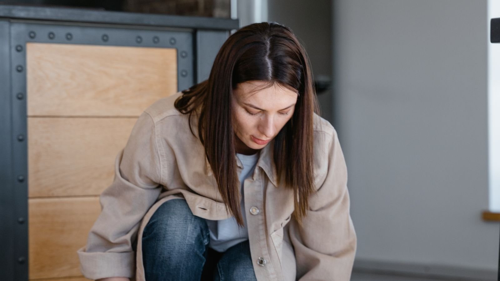 Woman lifting a round robot vacuum off a tiled floor for cleaning