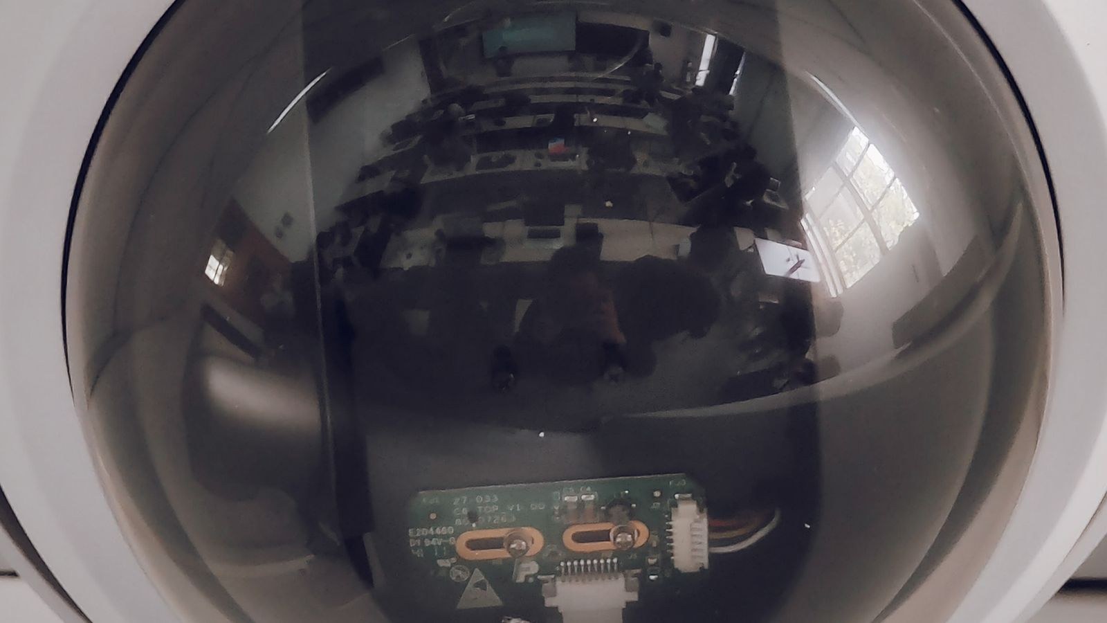 Close up of a dome security camera lens cover mounted indoors