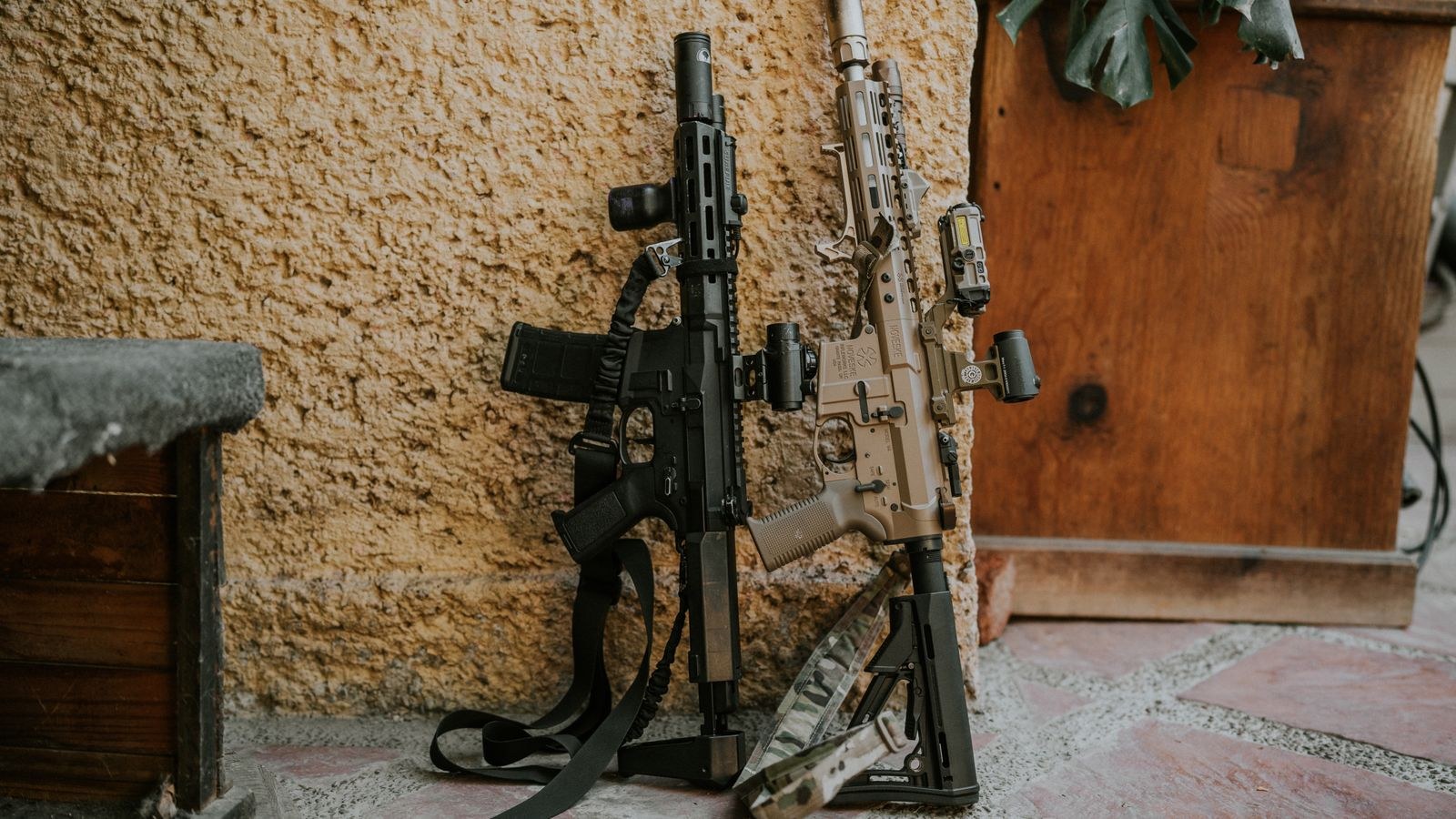 Two rifles leaning against a rustic wall in a dry storage area
