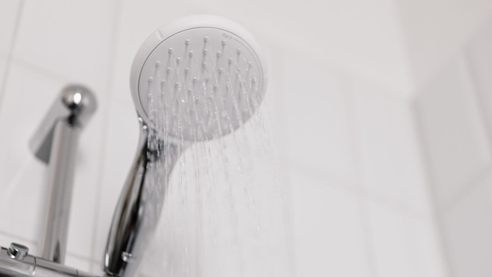 Shower head with limescale buildup spraying water in a bathroom
