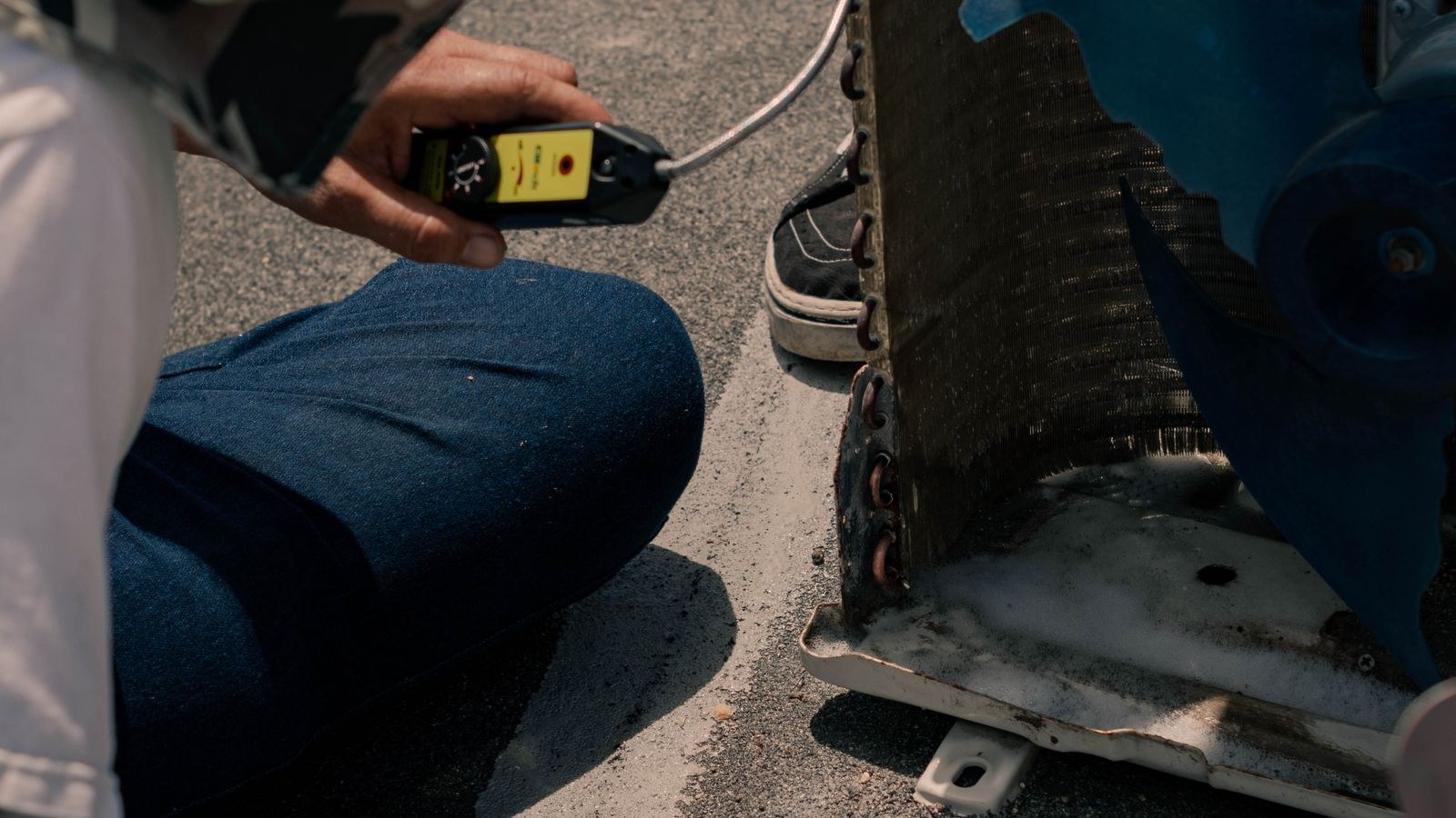 Technician testing an air conditioning unit with a multimeter during maintenance