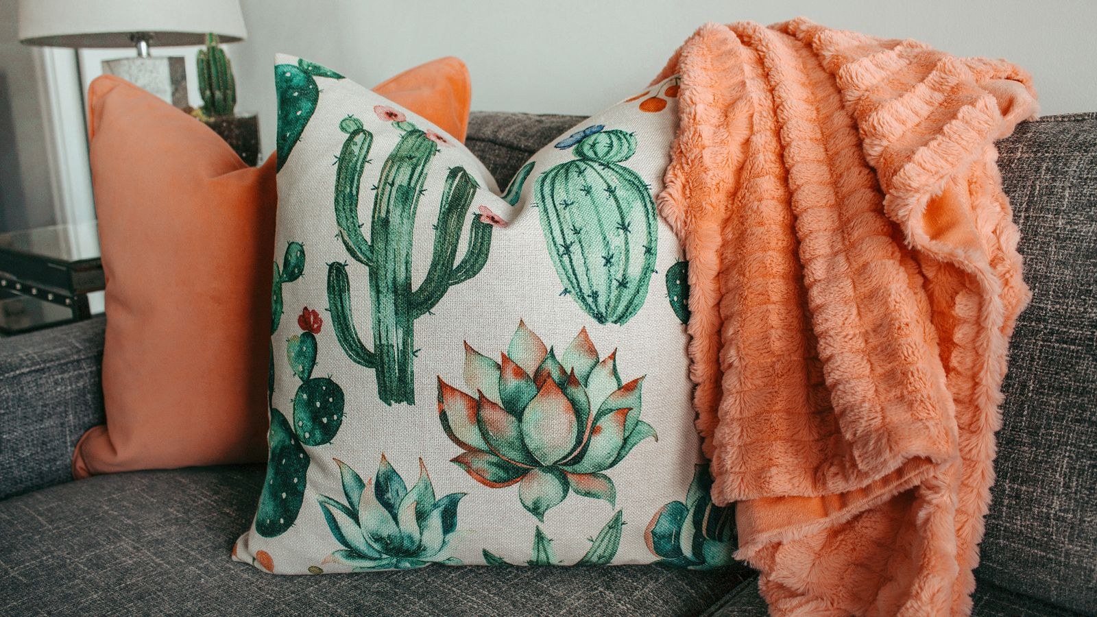 Cosy blanket and decorative pillows arranged on a modern couch