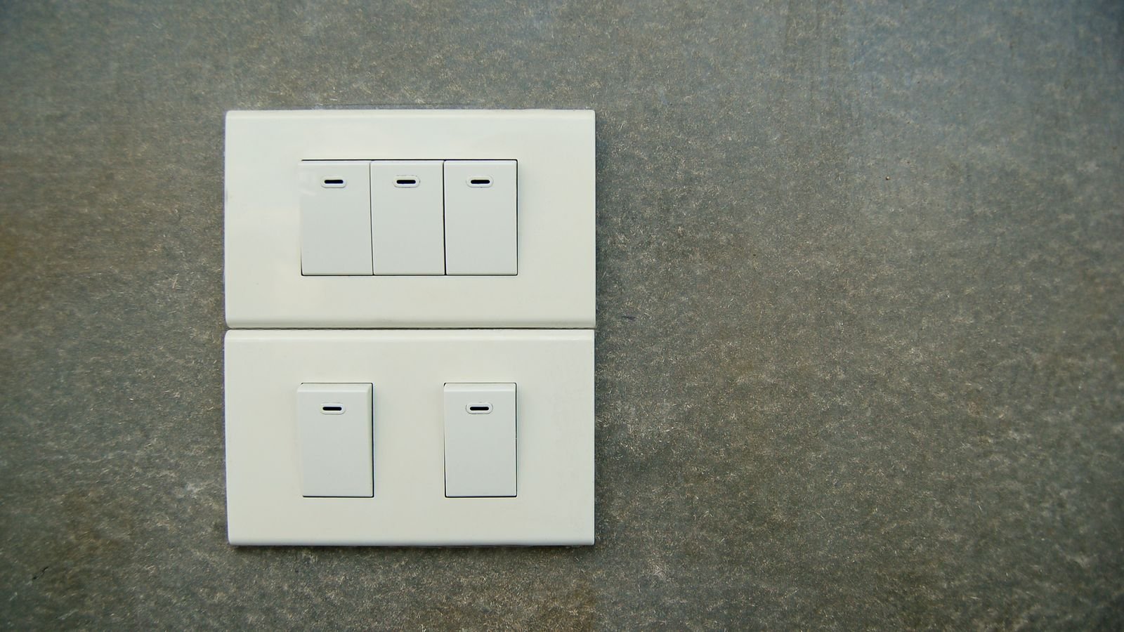 White electrical rocker switches mounted on a textured wall