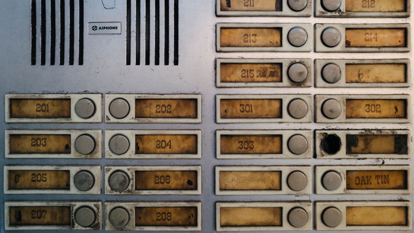 Worn apartment doorbell and intercom panel with corroded buttons