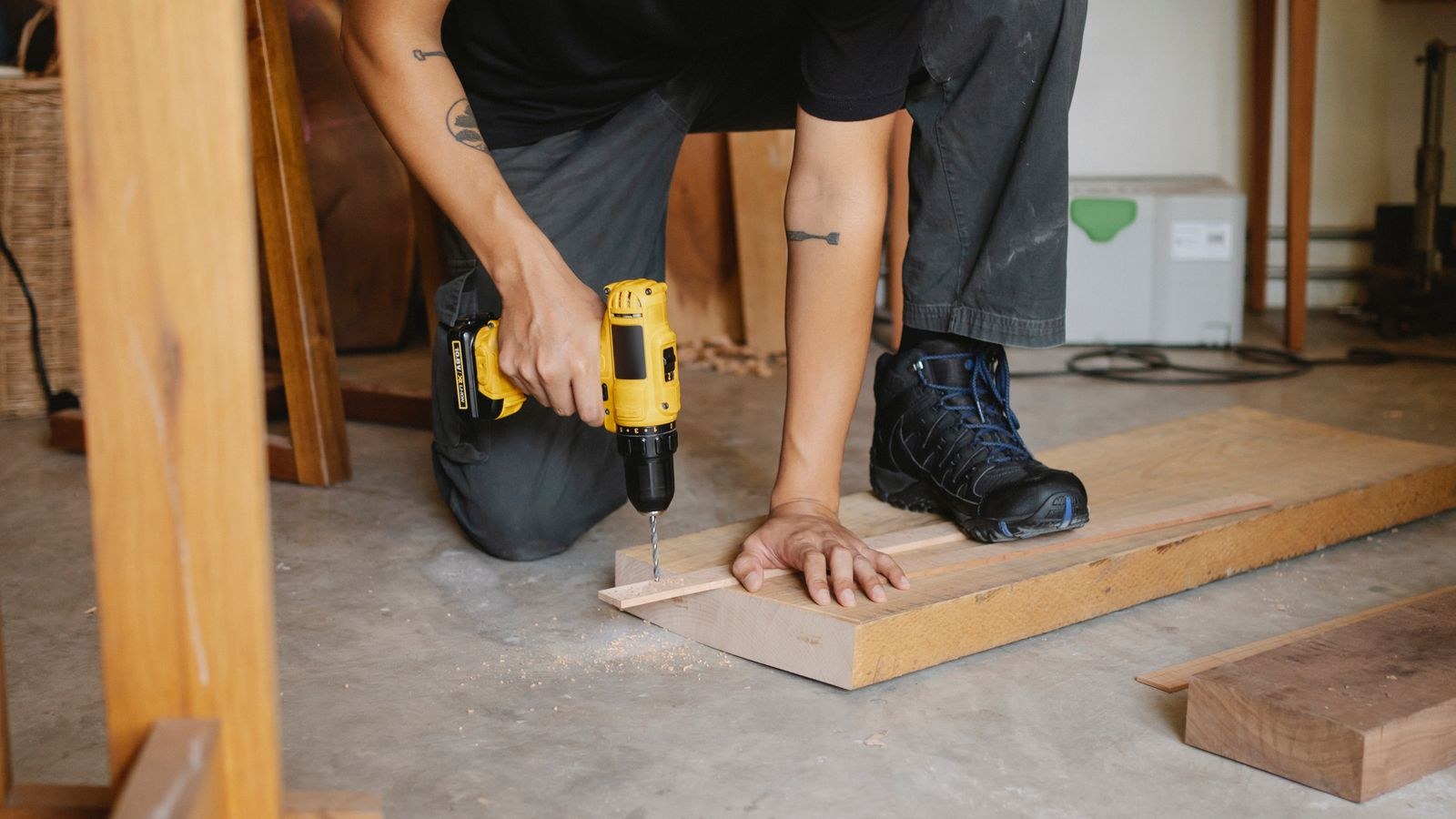 Person drilling into a timber panel with a screwdriver during furniture repair