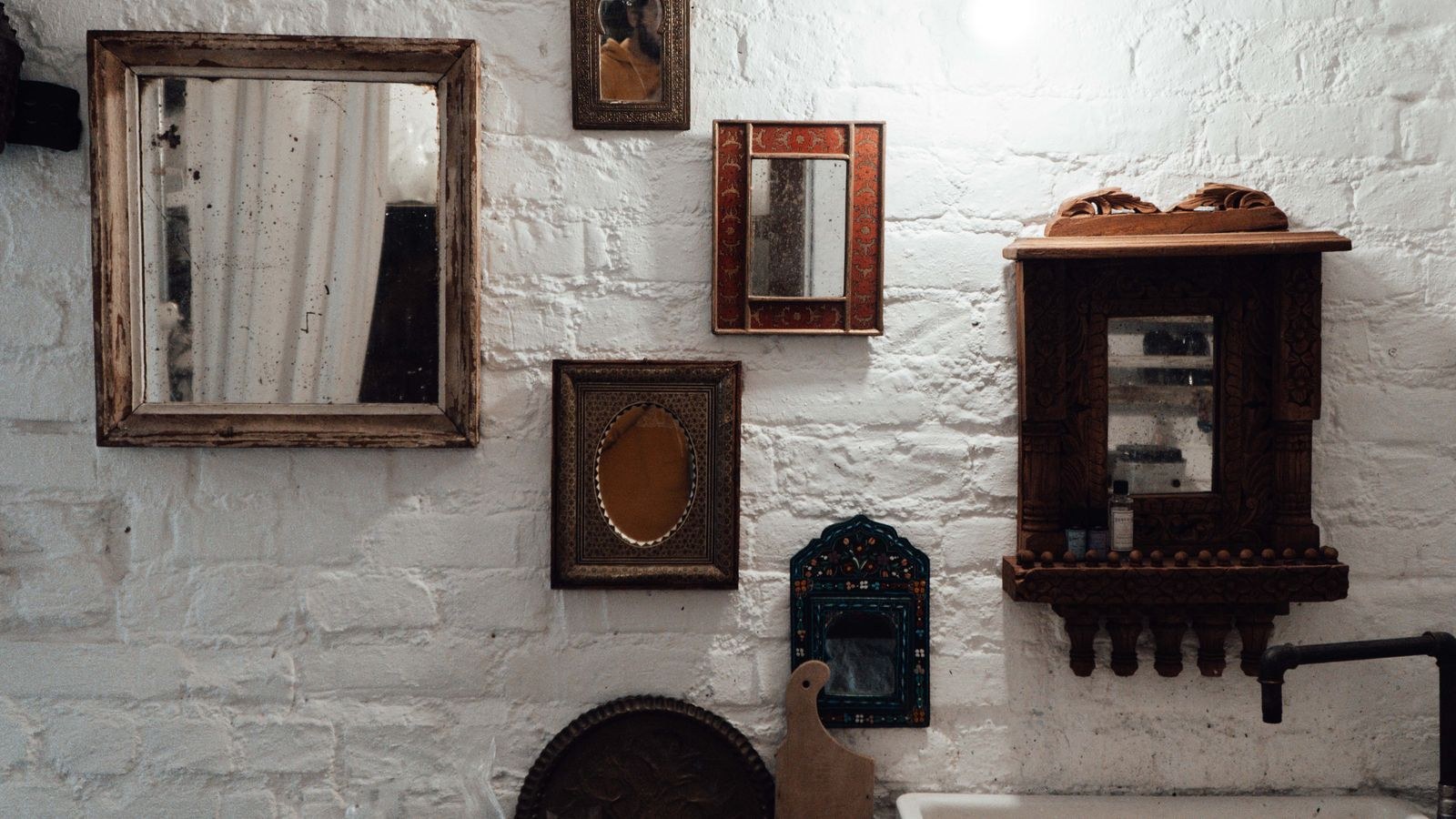 Wall mirror hung above a console with wall lighting in a bright room