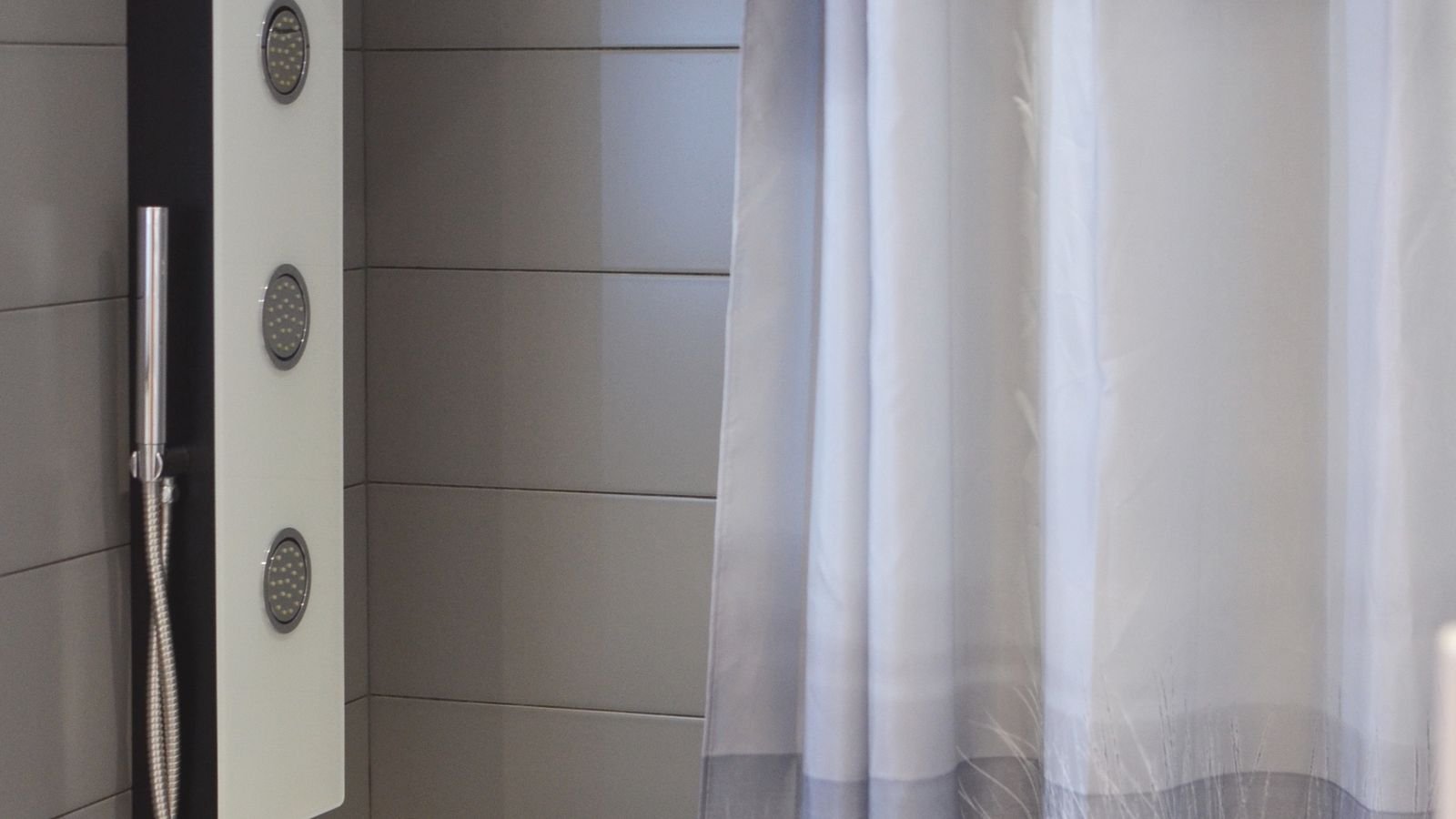Modern bathroom shower cabin with curtain against grey tiled walls