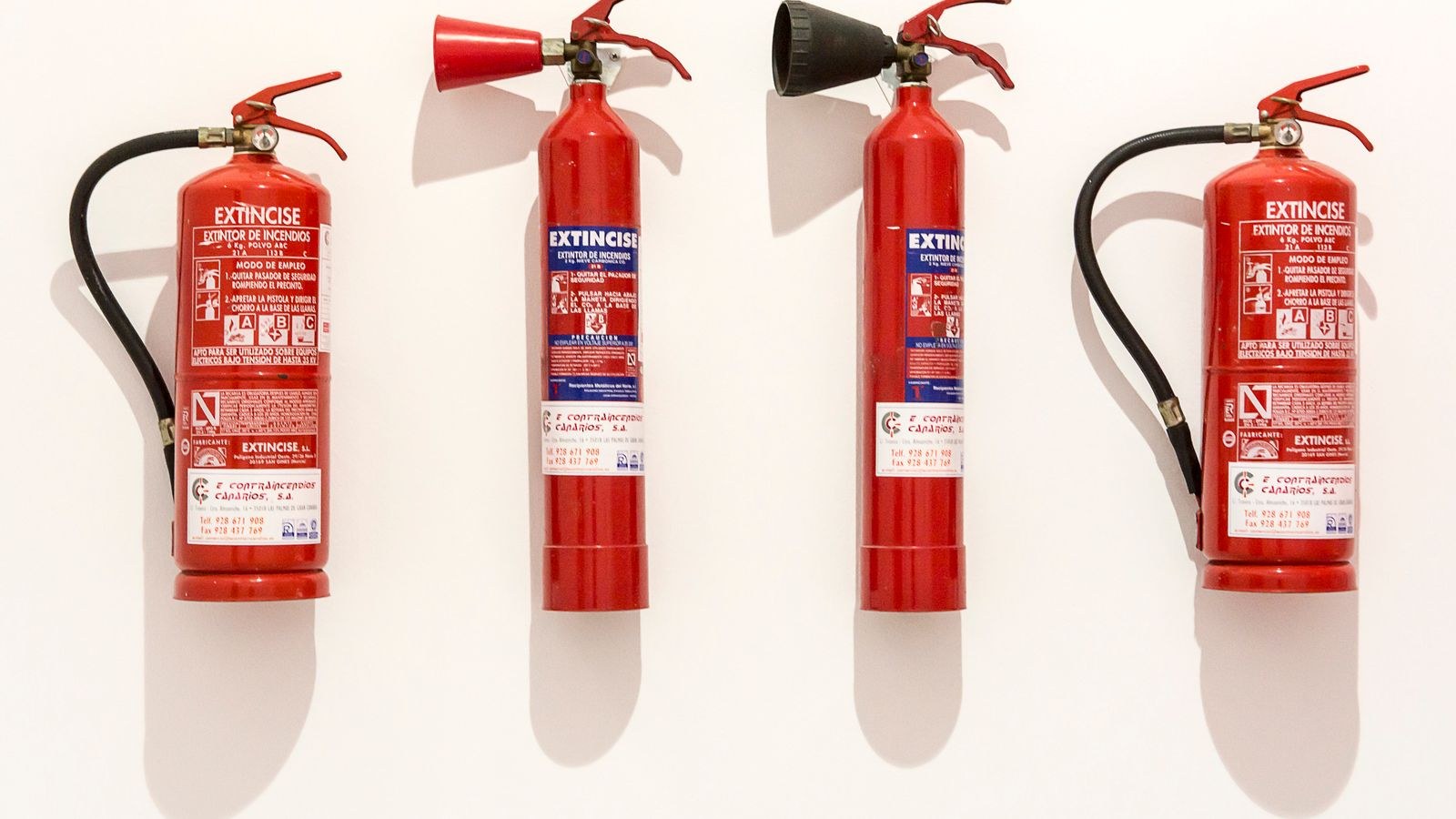 Row of red fire extinguishers hanging on a wall for regular safety checks