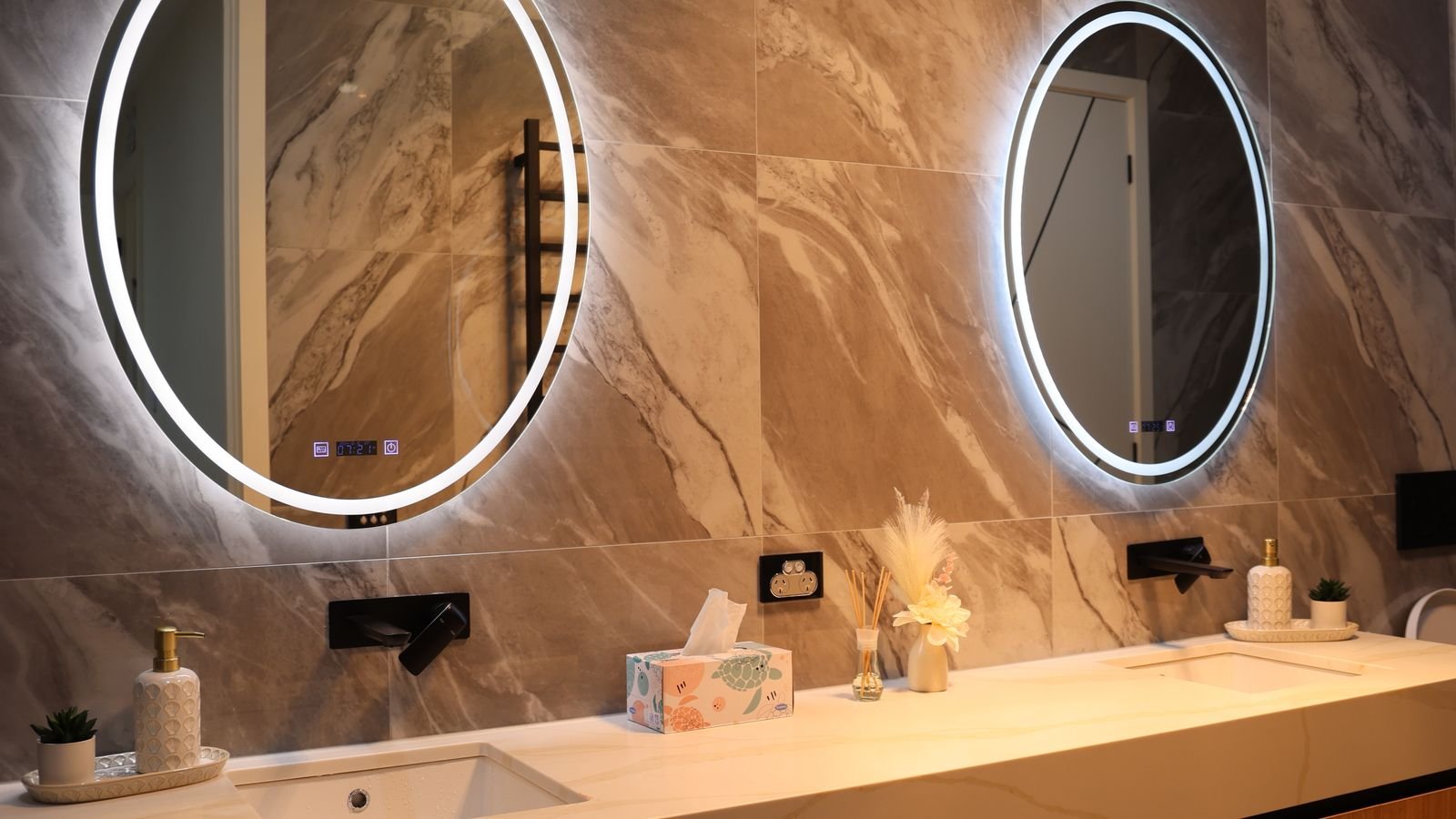 Double bathroom vanity with backlit mirrors providing even facial lighting