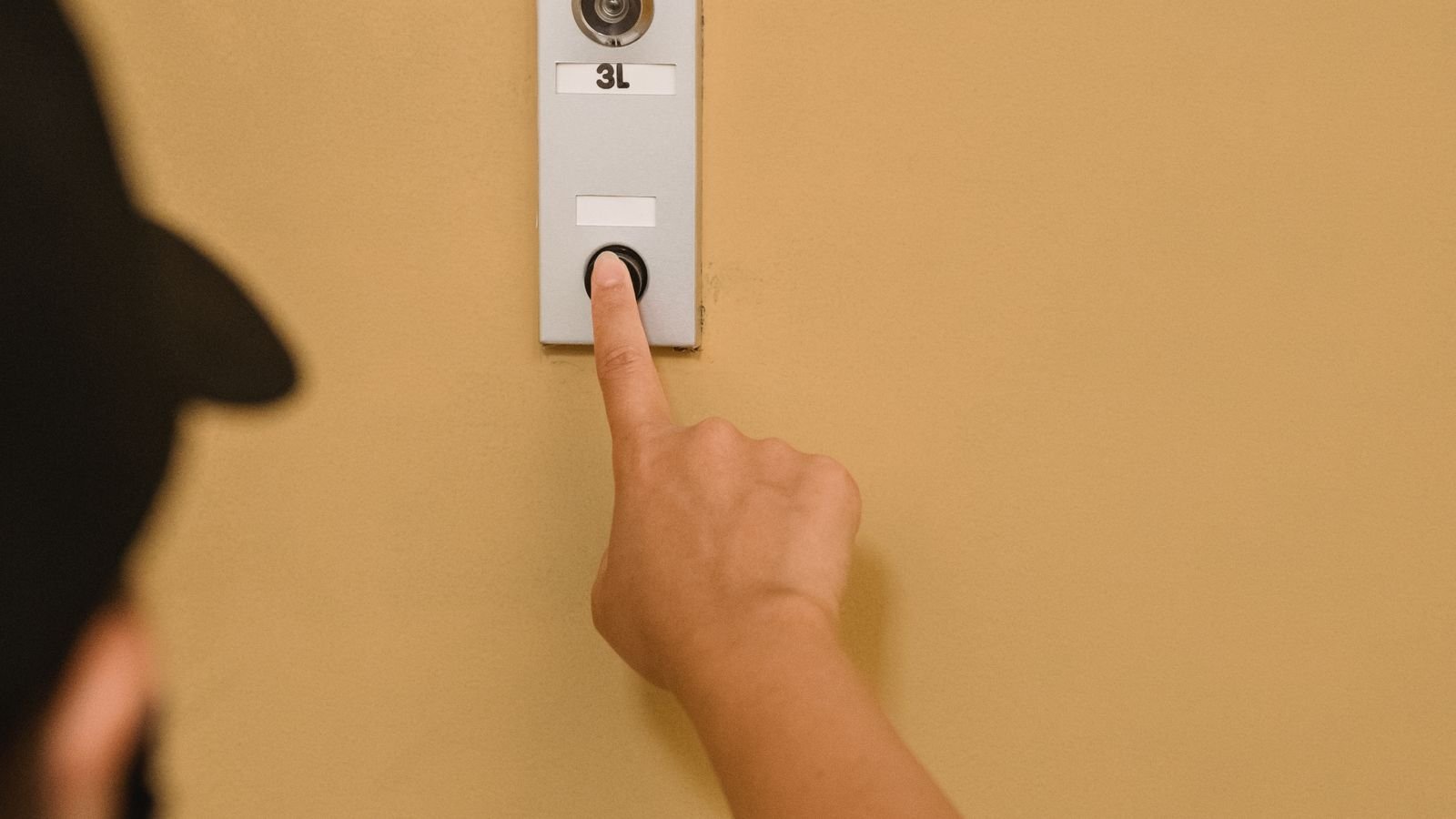 Person pressing a wireless doorbell button at a front door