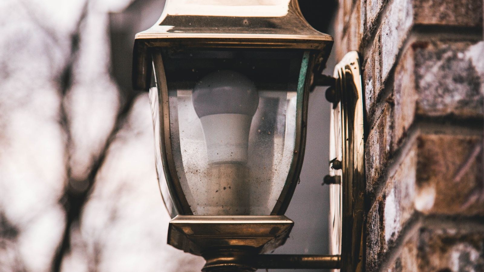 Outdoor wall lantern porch light fixture mounted on an exterior brick wall