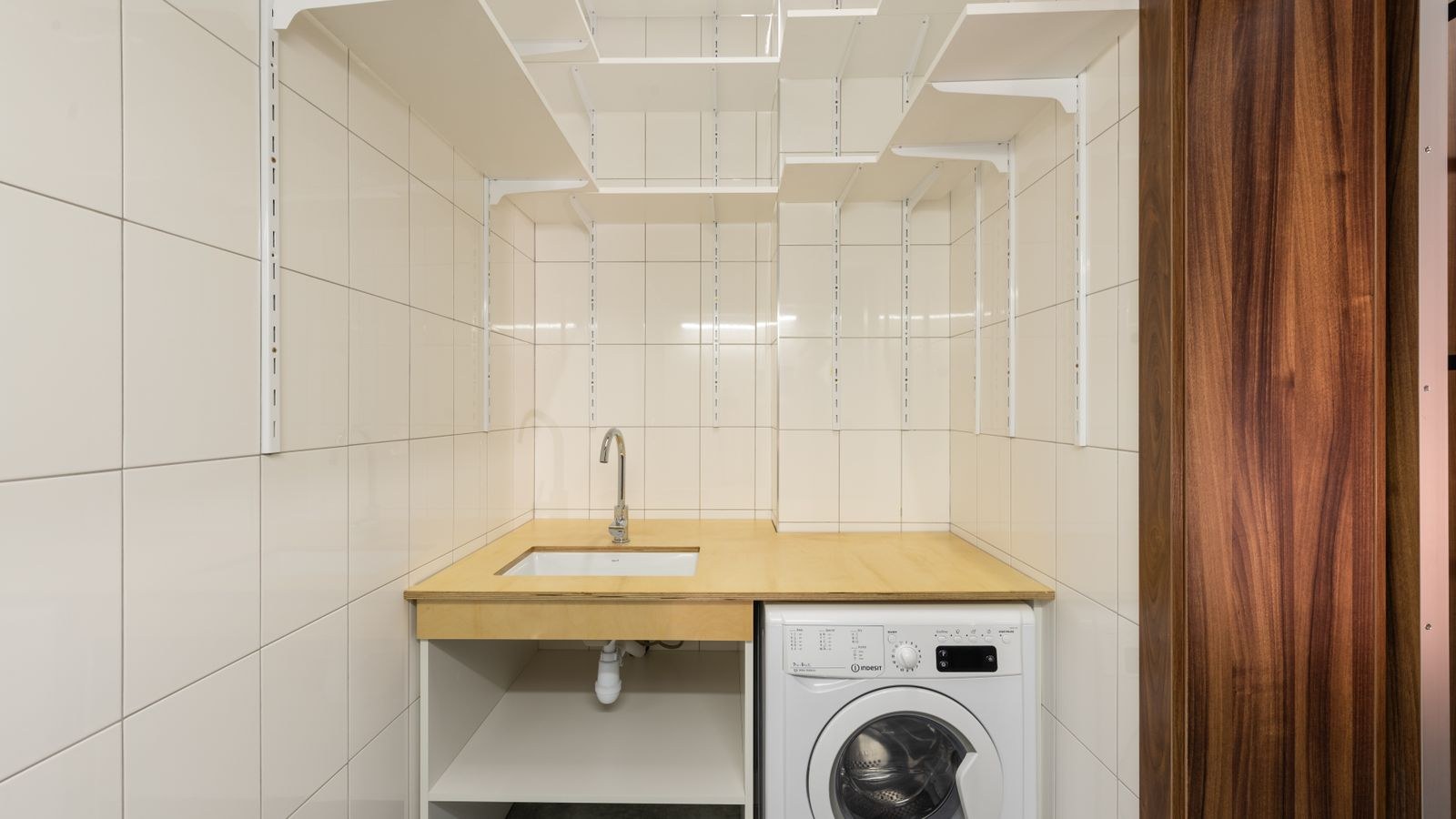 Compact laundry space with a washing machine and open shelving in an apartment