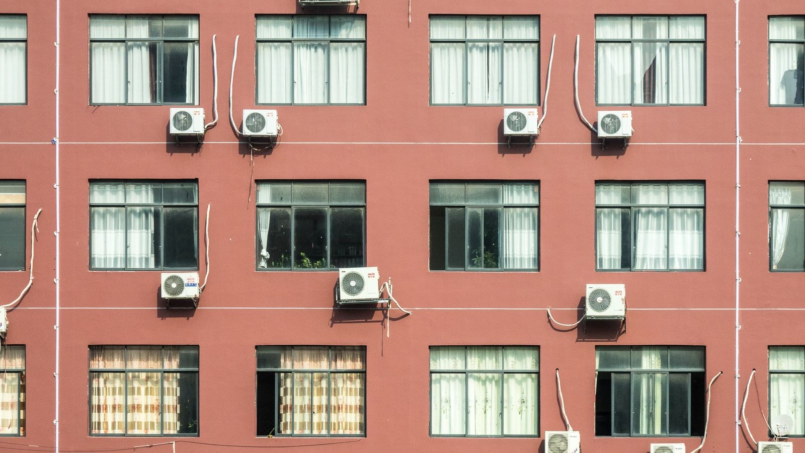 Brick apartment building exterior with several window air conditioners installed