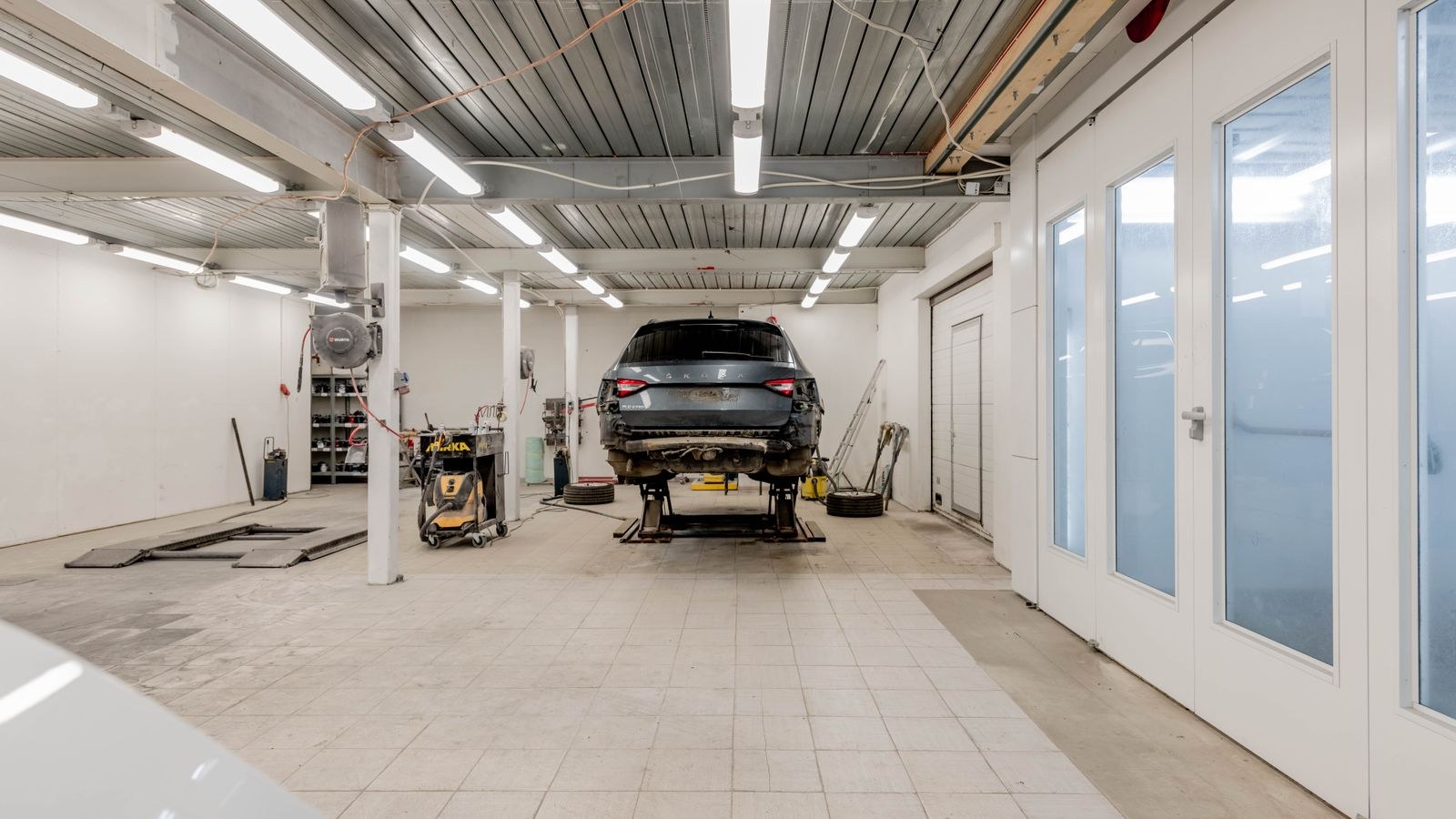 Well lit garage bay with a vehicle on a hydraulic lift