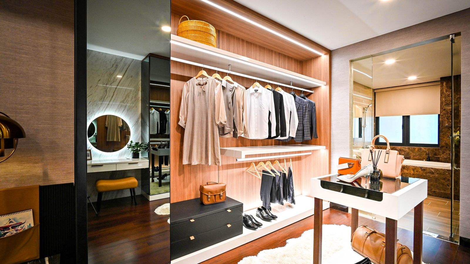 Organized walk-in closet with clothing lit by concealed fixtures