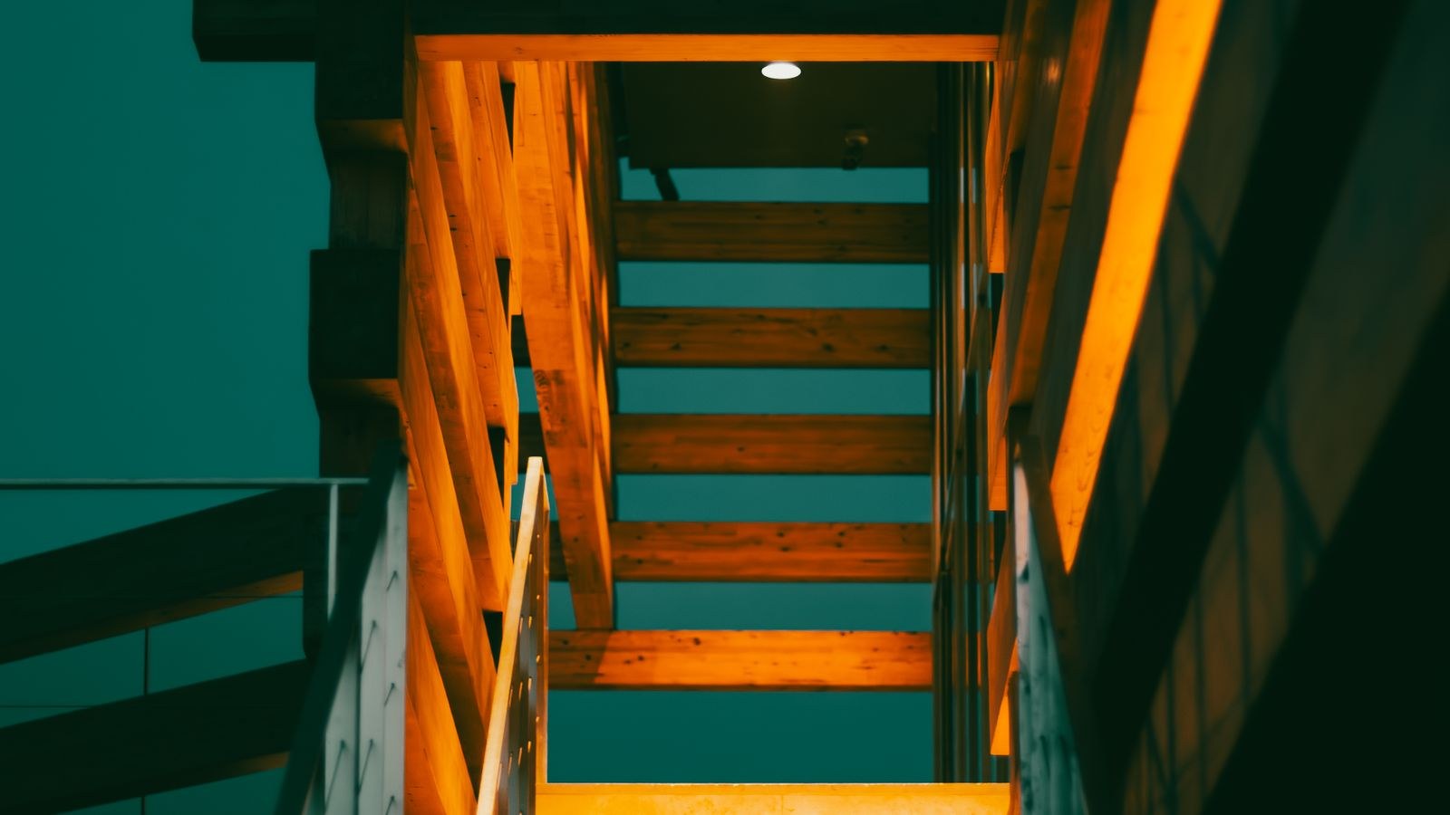 Wooden indoor staircase illuminated by warm accent lighting at night