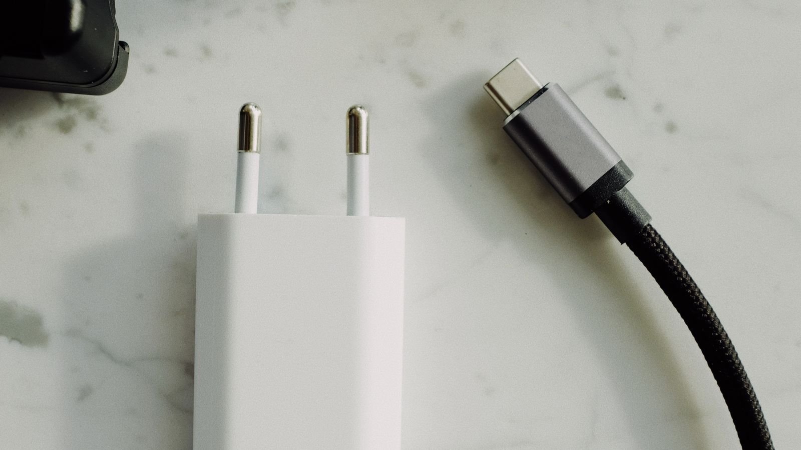 USB charging cable plugged into a wall socket charging a mobile phone
