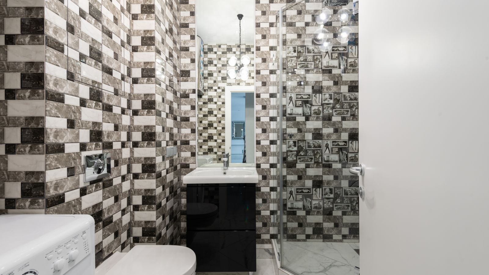 Small windowless bathroom with recessed ceiling lights and bright reflective tiles