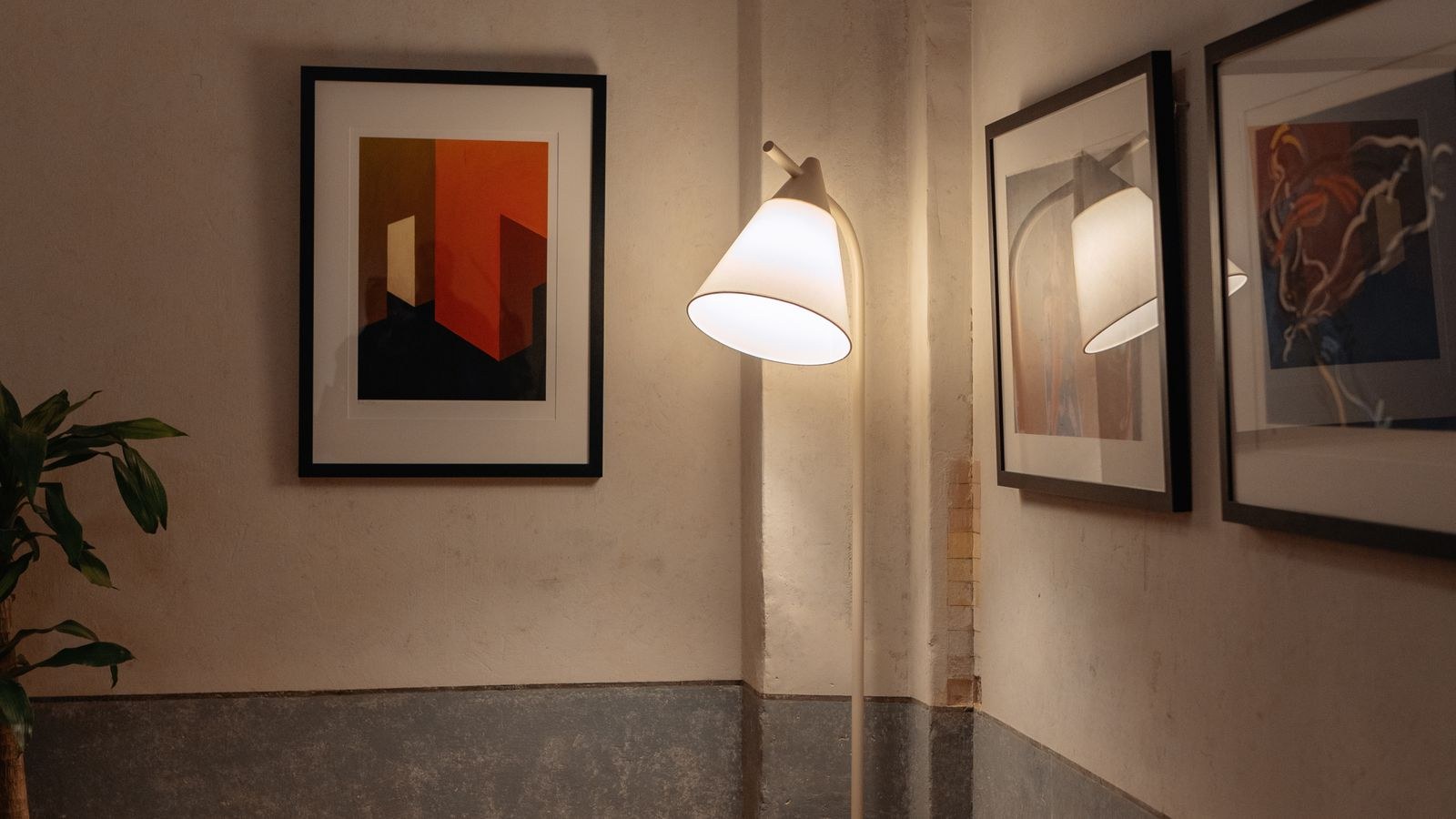 Corner of a room with artwork and a soft glow floor lamp casting shadows
