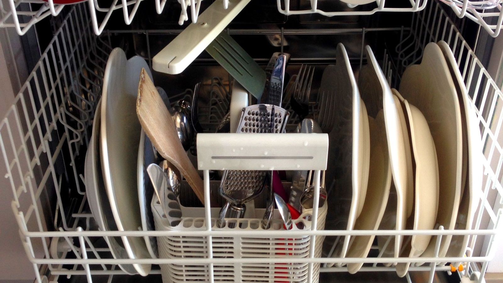 Top rack of a dishwasher loaded with glasses and mugs facing down