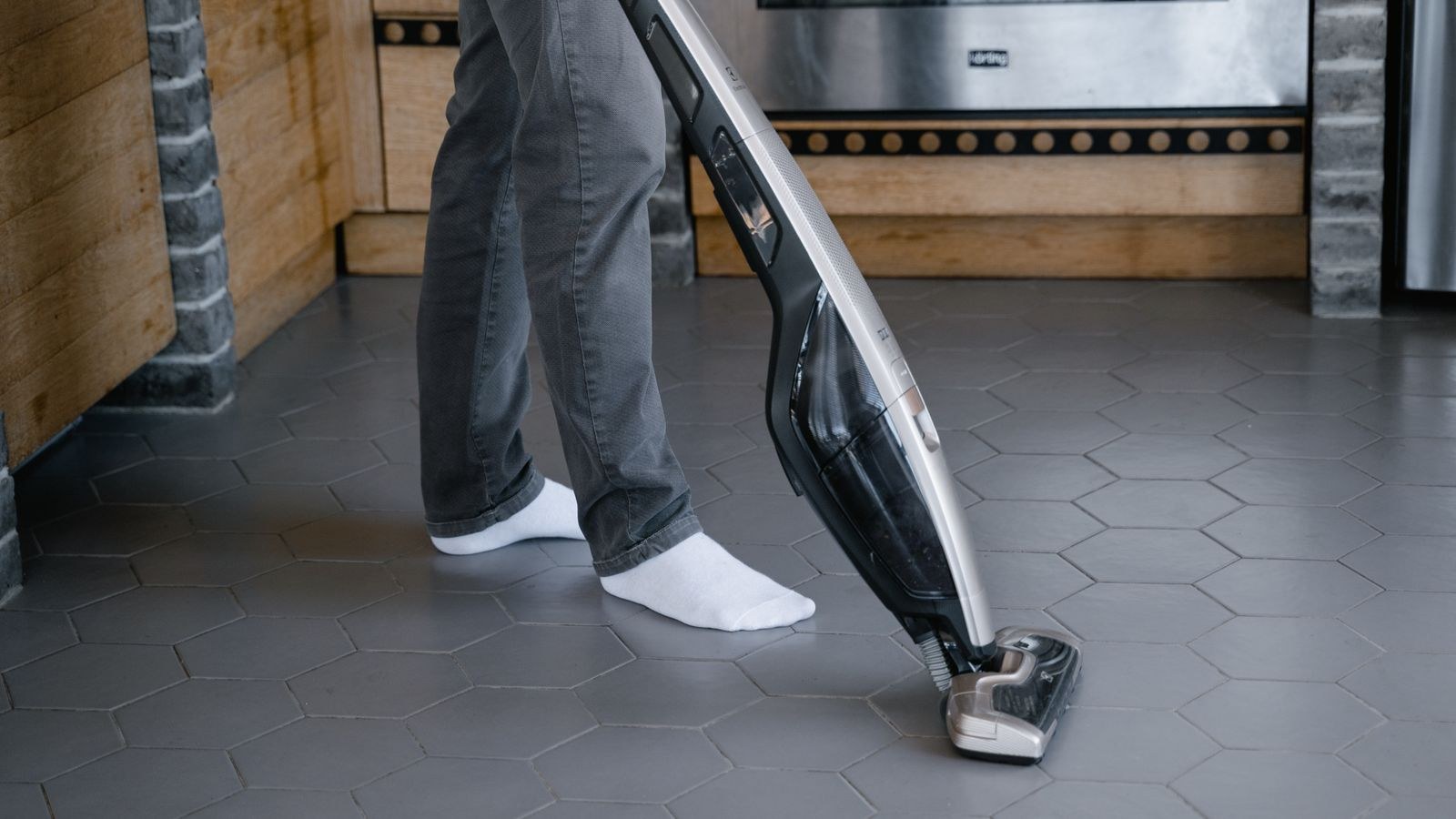 Person vacuuming a living room carpet with a cordless stick vacuum