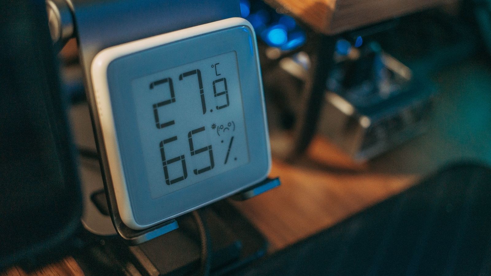Digital hygrometer on a desk displaying indoor humidity percentage and temperature