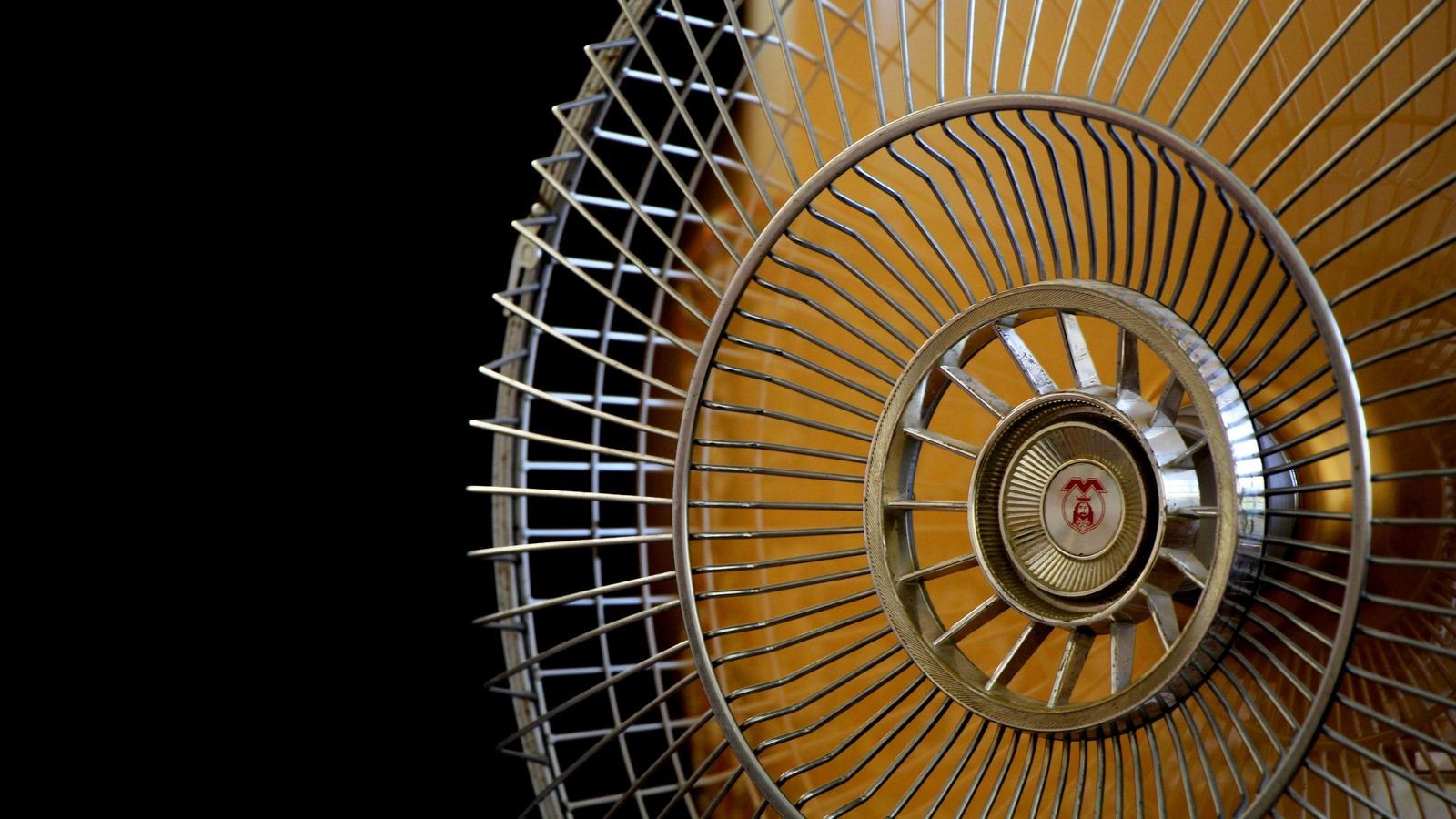 Close-up of an electric fan motor hub and metal blades showing the central shaft