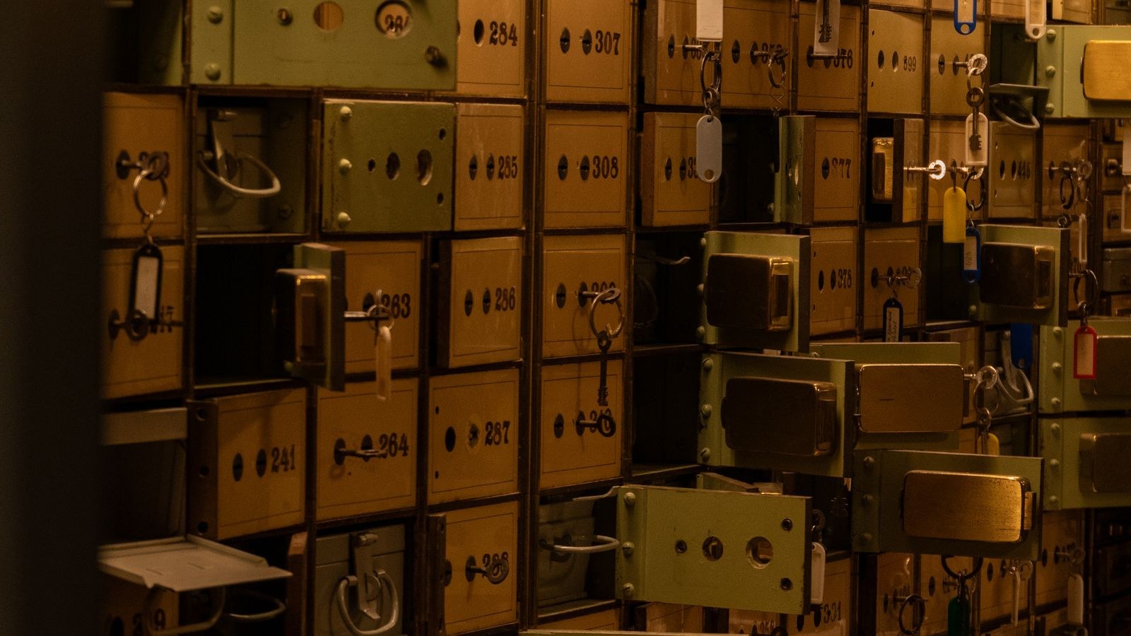 Dimly lit room lined with vintage security deposit boxes and keys