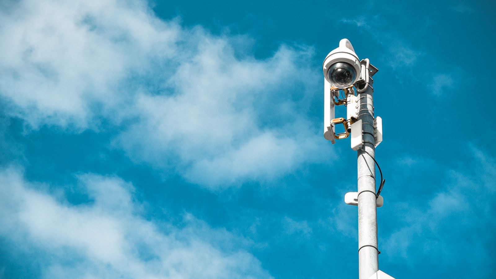 Security camera mounted on a pole under clear blue sky powered without an outlet