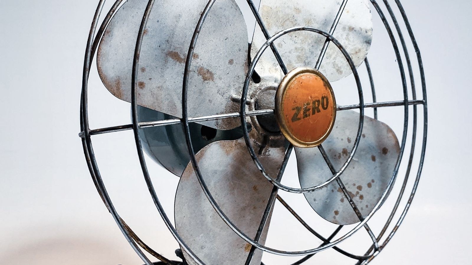 Close-up of an electric fan wire cage and blades showing the front grille fasteners