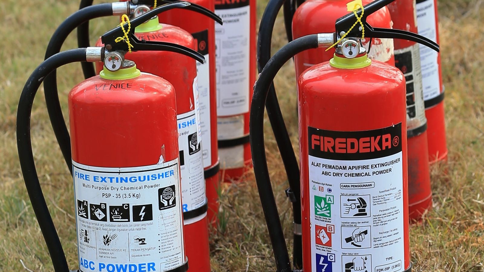 Several fire extinguishers lined up outdoors ready for servicing and disposal