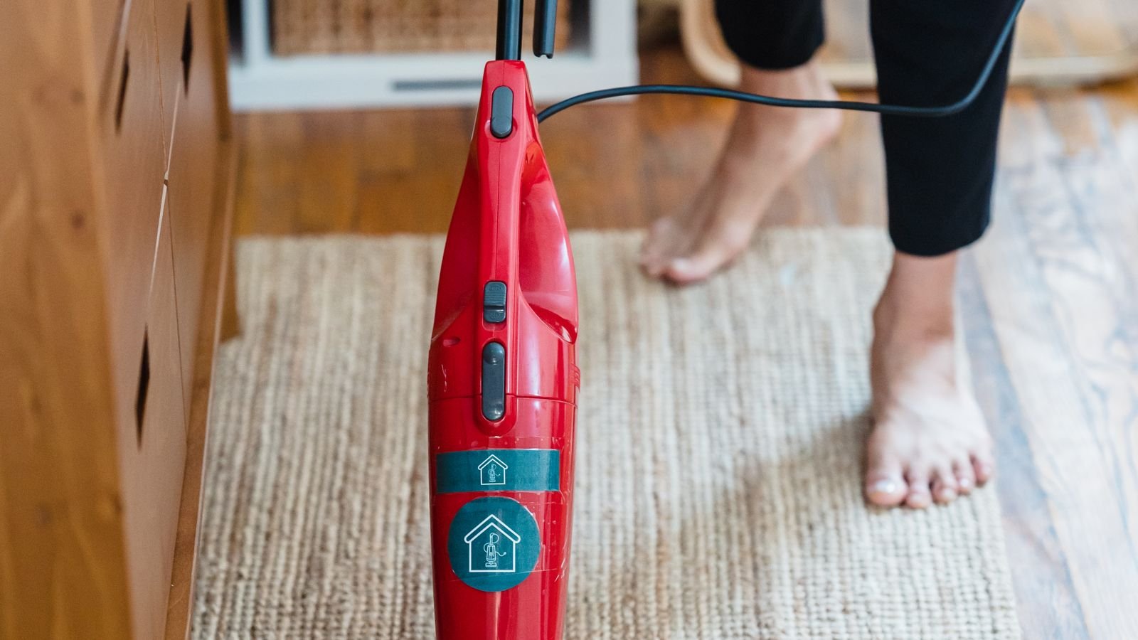 Person vacuuming a carpet barefoot to remove embedded pet hair