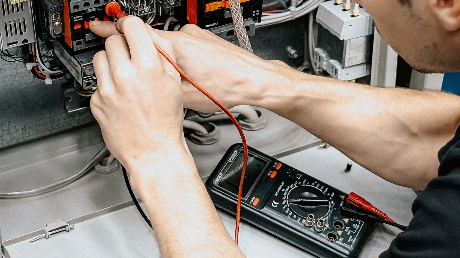 Electrician testing electrical connections with a meter during a switch replacement