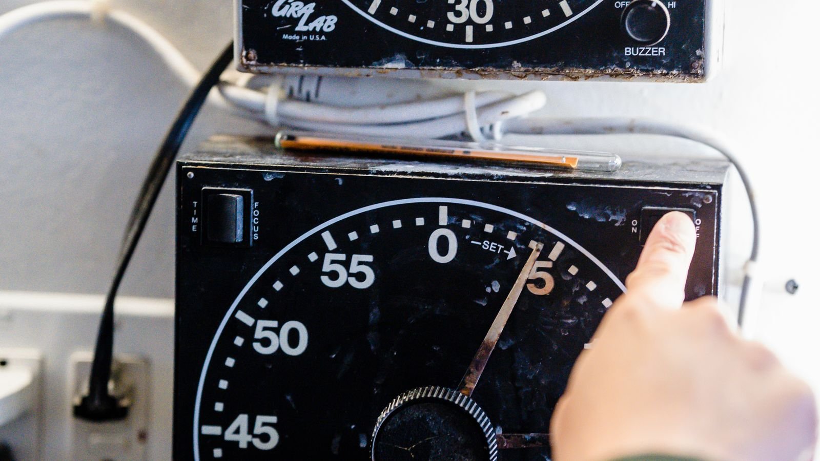Hand adjusting a mechanical analog timer dial mounted on a wall