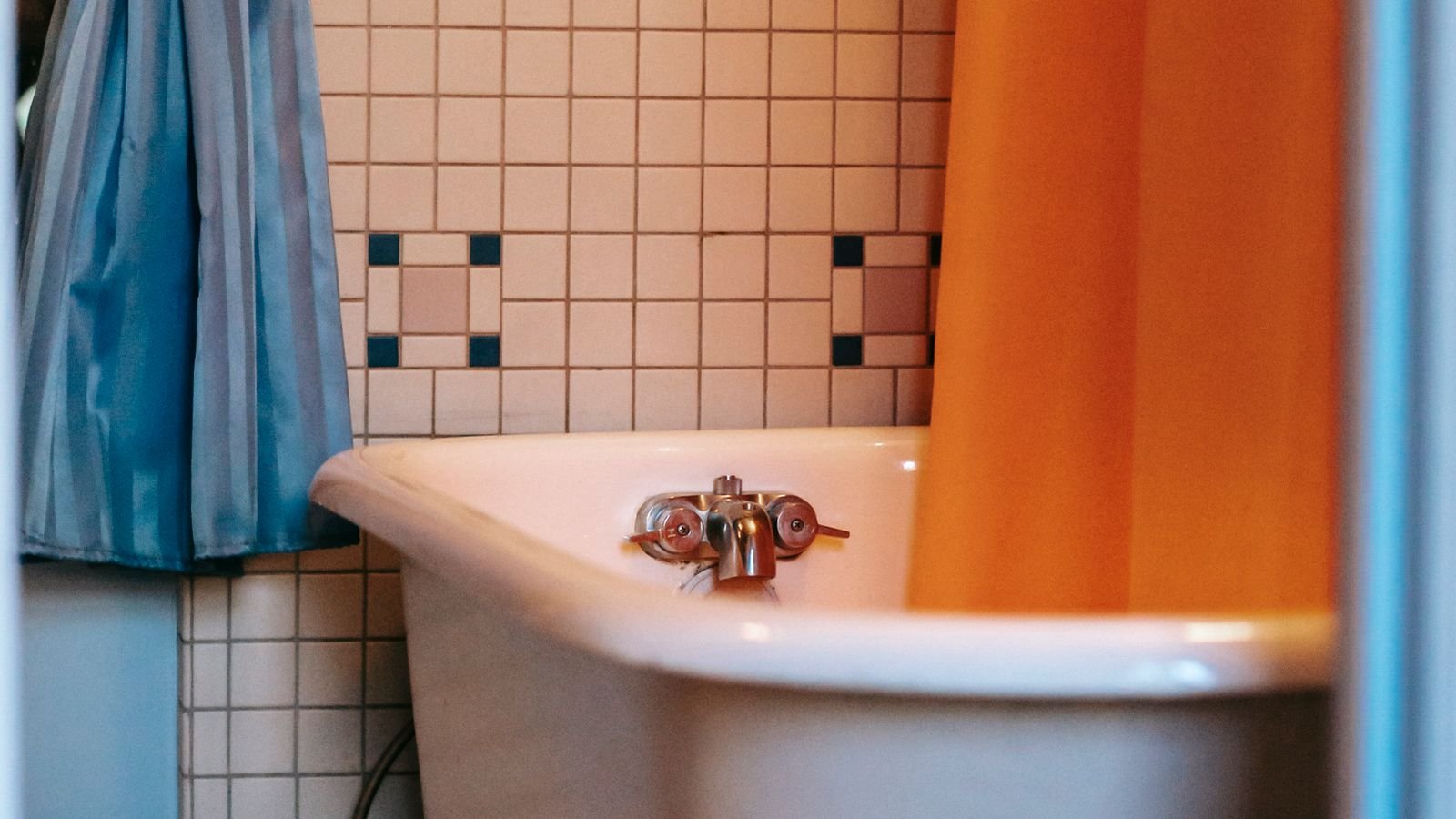 Classic claw foot bathtub with an orange shower curtain hanging from a rod