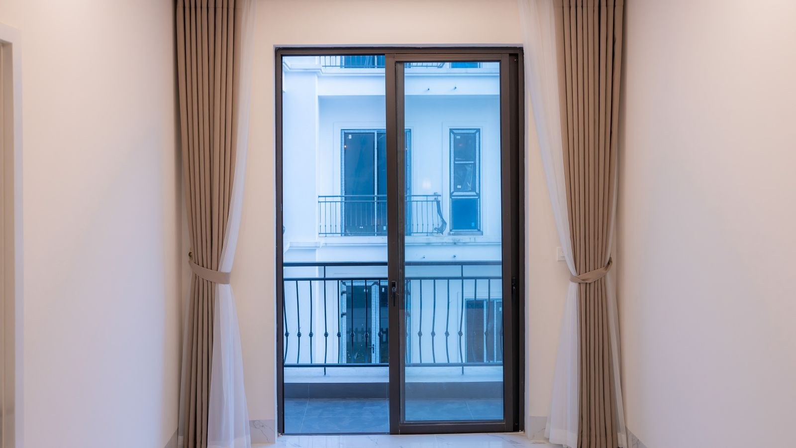 Large sliding glass door with curtains viewed from inside a secured home