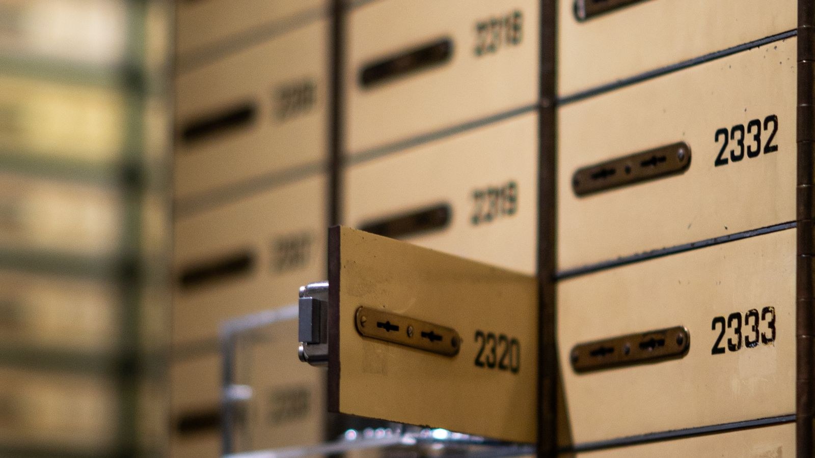 Bank of metal lockboxes with numbered dials in a secure vault room
