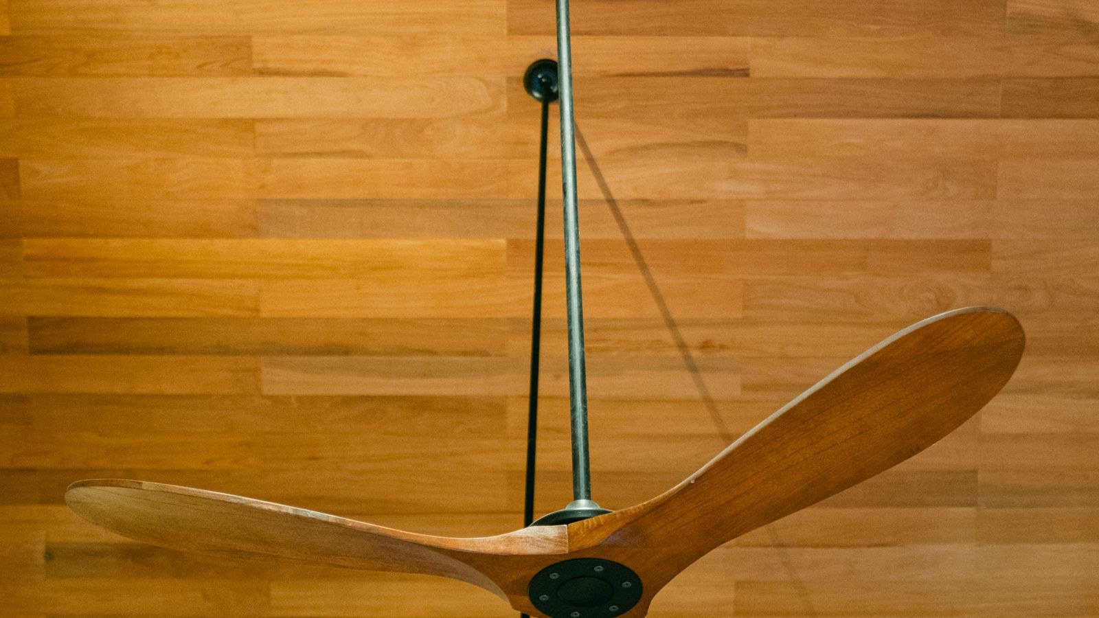 Modern wooden ceiling fan mounted on a wood ceiling in a living space